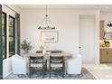 Elegant dining room features a modern chandelier, a wooden table with stylish chairs and view to exterior at 4395 N 203Rd Ave, Buckeye, AZ 85396