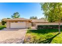 Charming single-story home with a brick facade, lush lawn, and a two-car garage at 10103 W Saddle Ridge Dr, Sun City, AZ 85373