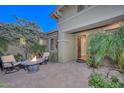 Cozy front patio with an outdoor fireplace, seating, and lush greenery at 12859 W Calle De Baca --, Peoria, AZ 85383