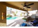 Covered patio with ceiling fan, outdoor kitchen, and a view of the sparkling pool at 14258 W Lisbon Ln, Surprise, AZ 85379