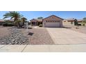 Single story home with desert landscaping, mature palm trees, and a two car garage at 15561 W Vista Grande Ln, Surprise, AZ 85374