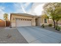 A lovely tan home showcases a well-maintained front yard, desert landscaping, and a spacious driveway at 20905 N Danielle Ave, Maricopa, AZ 85138