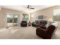 Comfortable living room featuring neutral walls, carpet flooring, and sliding glass doors leading to outdoor pool at 20905 N Danielle Ave, Maricopa, AZ 85138