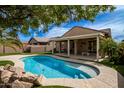 Inviting backyard showcasing a sparkling pool, a covered patio, and lush landscaping with palm trees at 346 E Red Mesa Trl, San Tan Valley, AZ 85143