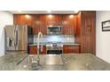 Close-up of kitchen with stainless steel appliances, a sink with a chrome faucet, and dark-stained wood cabinets at 4950 N Miller Rd # 122, Scottsdale, AZ 85251