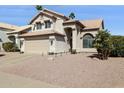 Inviting home featuring a two-car garage, desert landscaping and a cozy front porch with decorative pillars at 9264 E Hillery Way, Scottsdale, AZ 85260