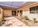 A charming patio area featuring custom stonework, mature plantings, and a covered awning at 9730 W Gulf Hills Dr, Sun City, AZ 85351
