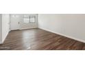 Bright living room featuring stylish wood floors, a large window, and a white front door at 10924 W Santa Fe Dr, Sun City, AZ 85351