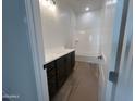 Bright bathroom featuring dual sinks, dark cabinets, a tub/shower combo, and tile flooring at 22813 E Alyssa Rd, Queen Creek, AZ 85142