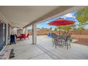 Inviting covered patio features an outdoor dining area and seating, perfect for entertaining or relaxing in style at 25320 W Heathermoor Dr, Buckeye, AZ 85326