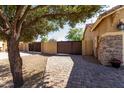 Paver walkway leading to a fenced side yard with stone ground cover and mature tree at 3431 E Canary Ct, Chandler, AZ 85286