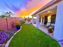 Beautiful backyard with lush green artificial turf, patio, and desert landscaping perfect for relaxing and entertaining under the colorful sunset at 3921 E Runaway Bay Pl, Chandler, AZ 85249