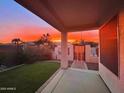 Covered backyard patio view shows beautiful sunset, green grass, and decorative iron gate at 3921 E Runaway Bay Pl, Chandler, AZ 85249