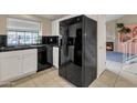 Kitchen featuring a black refrigerator, white cabinets, black counters and view to Gathering room with fireplace at 4901 E Kelton Ln # 1227, Scottsdale, AZ 85254