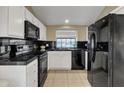 Bright kitchen with black appliances, white cabinets, tile flooring and black countertops at 4901 E Kelton Ln # 1227, Scottsdale, AZ 85254