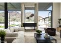 Bright living room with fireplace and expansive views of the outdoor pool and desert landscape at 5287 N Invergordon Rd, Paradise Valley, AZ 85253