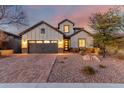 Beautiful home exterior featuring a well-manicured yard, brick driveway, and warm lighting at 12918 W Caraveo Pl, Peoria, AZ 85383