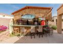 Outdoor tiki bar with a thatched roof, surfboard decor, and bar seating at 17470 W Gelding Dr, Surprise, AZ 85388