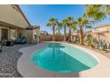 Inviting backyard pool surrounded by lush palm trees, perfect for relaxing or entertaining guests at 18026 W Carmen Dr, Surprise, AZ 85388