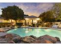 Gorgeous pool with stone accents and black wrought iron fence against a home with a covered patio at 2170 E Caroline Ln, Tempe, AZ 85284