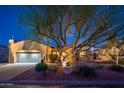 Charming single-story home featuring desert landscaping and a two-car garage, all illuminated at twilight at 22813 N Del Monte Dr, Sun City West, AZ 85375