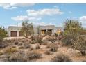 Desert home featuring natural landscaping, a three-car garage, and Southwestern architecture at 30600 N Pima Rd # 24, Scottsdale, AZ 85266