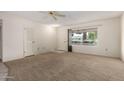 Neutral living room features a large window, carpet, and a ceiling fan at 9614 W Pleasant Valley Rd, Sun City, AZ 85351