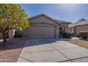 Inviting home exterior featuring a spacious driveway, desert landscaping and a mature orange tree at 16167 W Cottonwood St, Surprise, AZ 85374