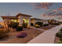Charming single-story home with well-manicured front yard and walkway lighting, creating a warm ambiance at 23145 E Stonecrest Dr, Queen Creek, AZ 85142