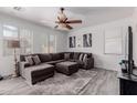 Spacious living room with a large sectional sofa, ceiling fan, and neutral decor at 44165 W Kramer Ln, Maricopa, AZ 85138