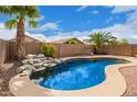 Backyard pool with a rock waterfall feature surrounded by palm trees creating a relaxing oasis at 8867 E Avenida Las Noches --, Gold Canyon, AZ 85118