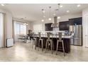 Modern kitchen featuring a large island with seating, stainless steel appliances, and elegant pendant lighting at 10249 W Redbird Rd, Peoria, AZ 85383