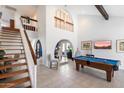 Bright living room with a soaring ceiling, a staircase, and an adjacent dining area with a pool table at 10800 N 101St St, Scottsdale, AZ 85260