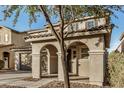 Warm home exterior featuring a covered porch with an arched entryway and two-car garage at 11918 W Yearling Ct, Peoria, AZ 85383