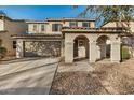 Inviting home exterior with a two-car garage, covered porch, and meticulously landscaped front yard at 11918 W Yearling Ct, Peoria, AZ 85383