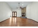 Open living room features hardwood flooring, ceiling fan, stone fireplace, and neutral wall color at 14401 N 60Th Pl, Scottsdale, AZ 85254