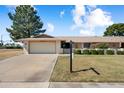 Inviting single-level home showcasing a two-car garage, a manicured lawn, and vibrant, mature landscaping at 18018 N Highwood Ct, Sun City, AZ 85373