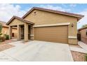 Low angle view of the attractive single-story home showcasing a two-car garage and covered entryway at 213 S 225Th Ln, Buckeye, AZ 85326