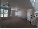A spacious living room with carpet, multiple windows, ceiling fans, and access to the staircase at 40232 W Marion May Ln, Maricopa, AZ 85138