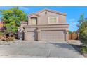 Beige two-story home with a three-car garage and well-maintained landscaping, under a clear blue sky at 648 W Cobblestone Dr, Casa Grande, AZ 85122