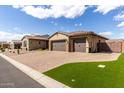 Exterior view of the three car garage with brick paver driveway and well manicured lawn at 7630 E Knoll St, Mesa, AZ 85207