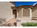 Close-up of the front door, including a neutral stucco exterior and xeriscaping at 10960 E Monte Ave # 164, Mesa, AZ 85209