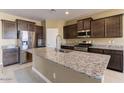 Spacious kitchen features a granite island, stainless steel appliances, and dark wood cabinets at 13812 W Remuda Dr, Peoria, AZ 85383