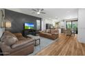 Open-concept living room with hardwood floors, a ceiling fan, and a modern TV wall at 18841 E Pelican Ct, Queen Creek, AZ 85142