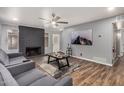 Living room features a modern sofa, fireplace, ceiling fan, and wood-look flooring for a cozy and stylish atmosphere at 2015 E Southern Ave # 2, Tempe, AZ 85282