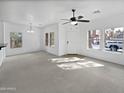 Open living space with neutral carpet, a ceiling fan, and abundant natural light from multiple windows at 3316 W Hayduk Rd, Laveen, AZ 85339