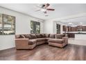Bright living area boasts dark wood floors and a plush brown sectional, with a glimpse into the kitchen at 3938 E Morrison Ranch Pkwy, Gilbert, AZ 85296