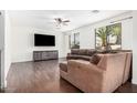 A cozy living room with hardwood floors, a ceiling fan, and a comfortable brown sectional sofa at 3938 E Morrison Ranch Pkwy, Gilbert, AZ 85296