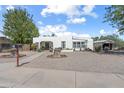 Street view of a single-story white home with gravel front yard, sidewalk, and mature trees at 100 Swilling Ave, Wickenburg, AZ 85390