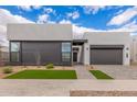 Striking modern home with a gray facade, large windows, and minimalist xeriscaped front yard at 10302 E Utah Ave, Mesa, AZ 85212